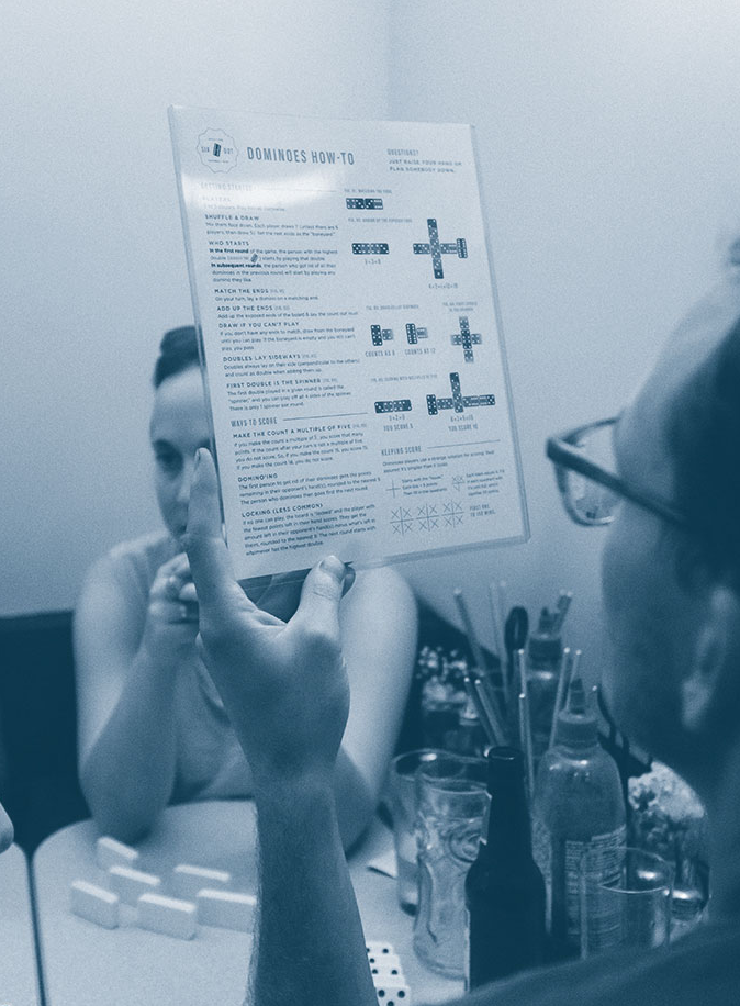 A person holding up domino instructions at a Six Dot event.